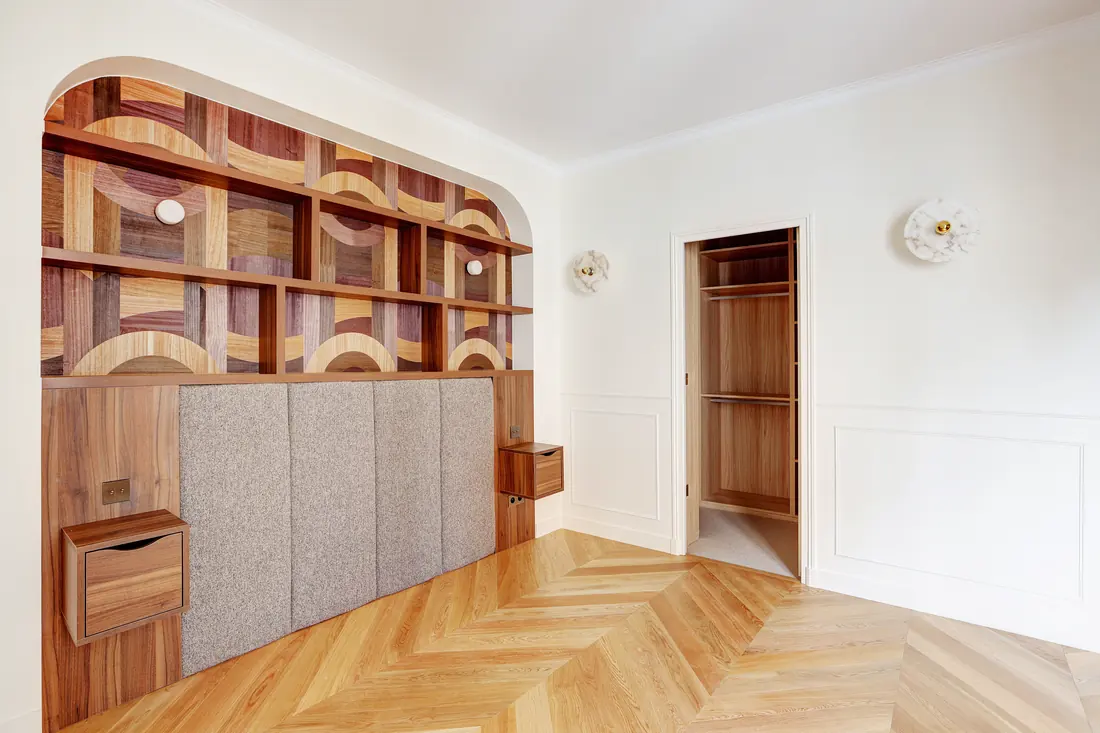 Vue large de la pièce avec bibliothèque sur mesure, soubassement mouluré et parquet